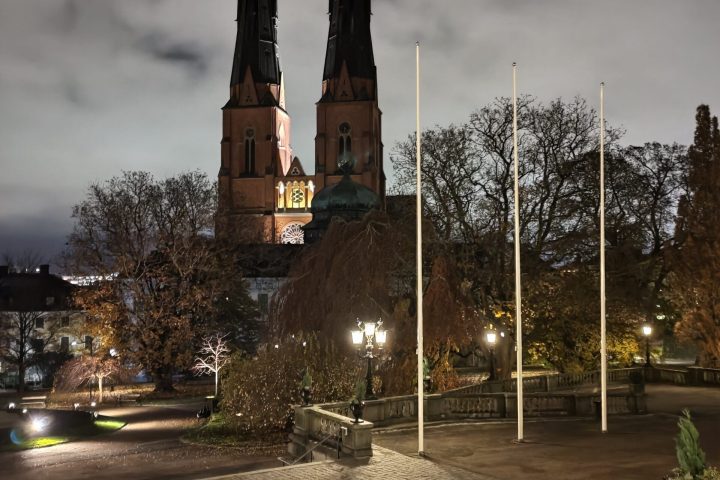 a tall tower with a clock on the side of a road